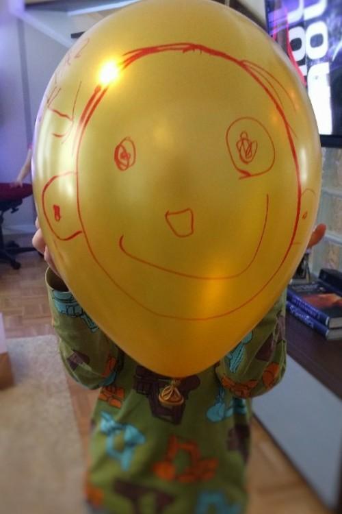 Lapsi pitelee ilmapalloa kasvojensa edessä.